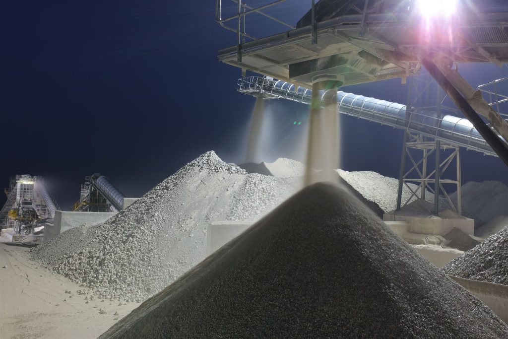 Planta de procesamiento de minerales iluminada de noche con fajas transportadoras